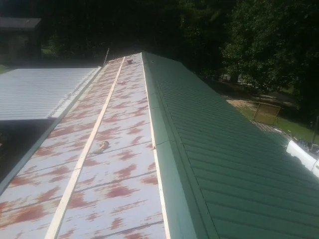 Old rusted panels beside newly installed green metal roofing — Wind Damage Roof Repair by Roofing Brothers in Geigertown
