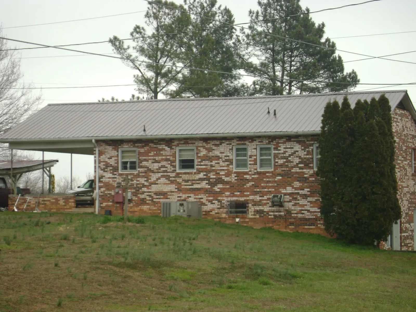 Gray metal roof on a brick split level home with a carport in Geigertown