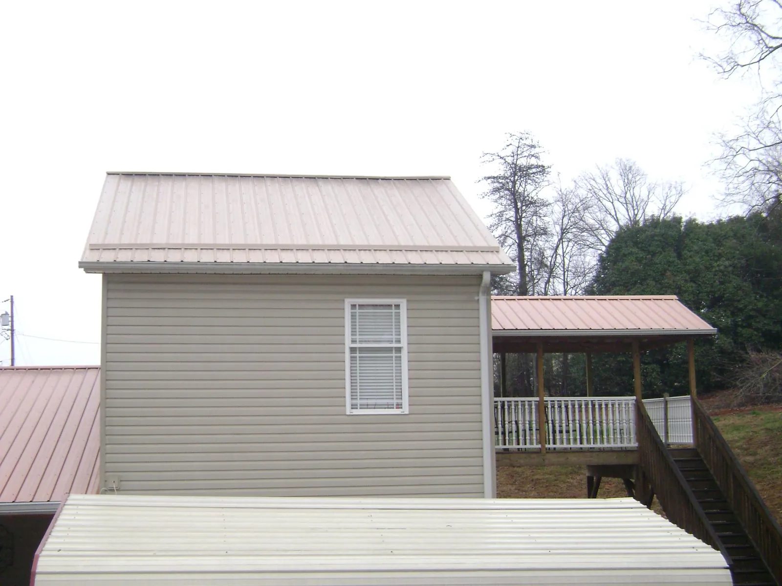 Tan metal roofs on a two story addition and attached porch, from a Roof Replacement job in Geigertown
