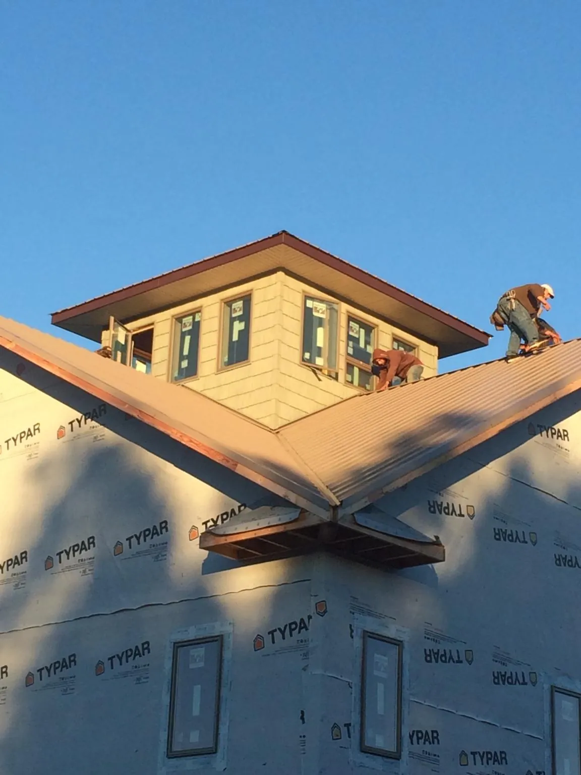 Roofers working around a rooftop cupola on a new metal roof at sunset — Roof Waterproofing in Geigertown by Roofing Brothers